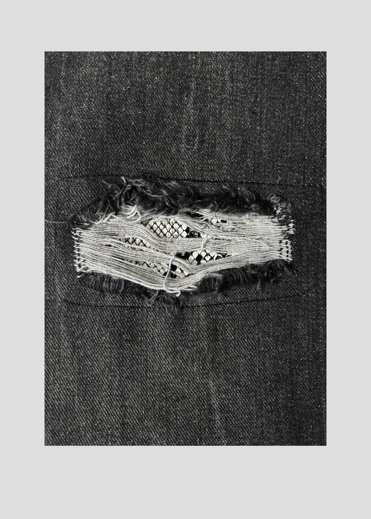 Close-up of a distressed rip in the ONEFATE Snake Jeans revealing snake-pattern fabric underneath