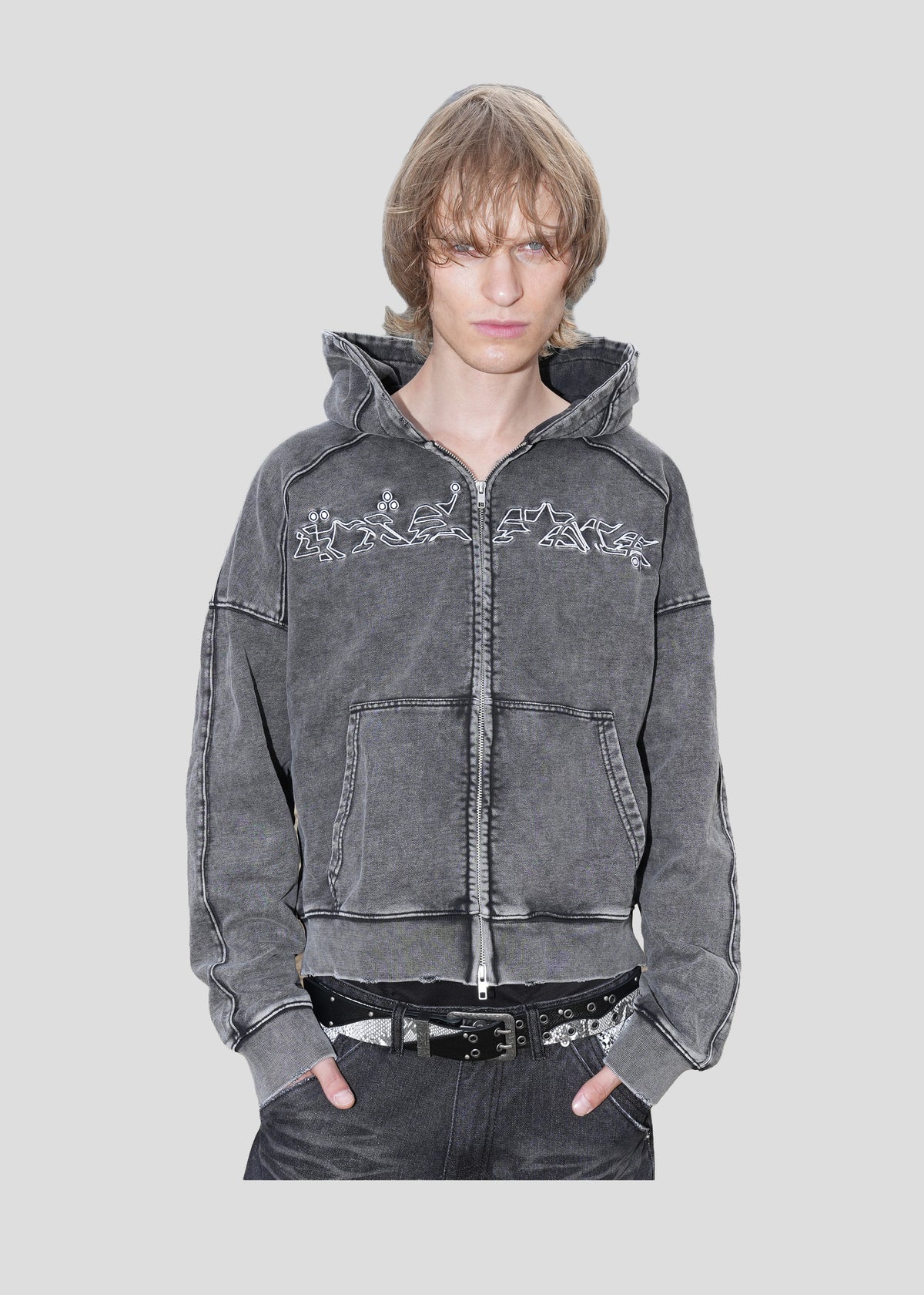 Model wearing the ONEFATE Washed Zip-Hoodie open, with a studded snake-pattern belt and dark jeans